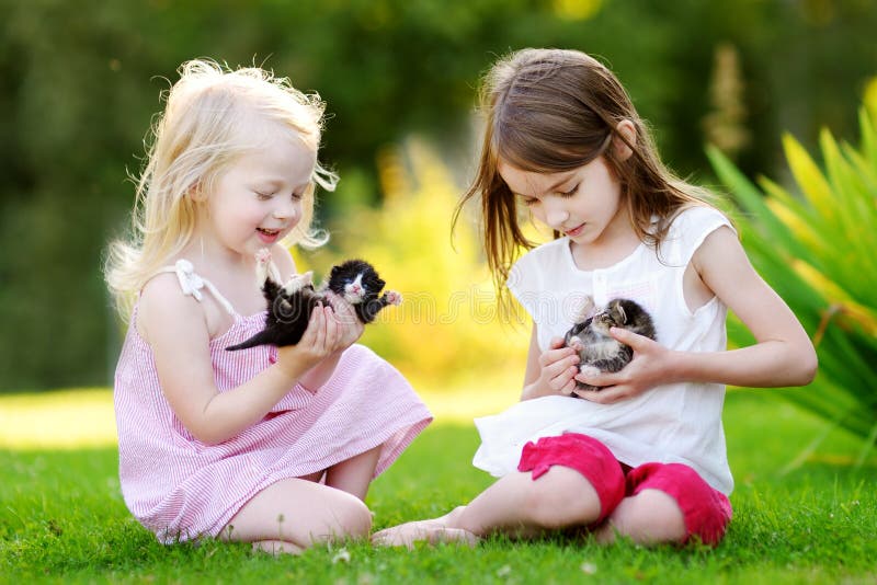 Two adorable little sisters playing with small newborn kittens royalty free stock images
